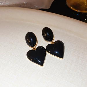 Detailed macro of vintage oval heart earrings with black enamel and gold plated edges