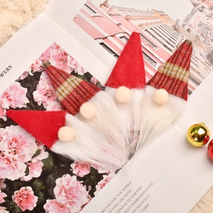 Set of four handmade Christmas gnome ornaments with red and plaid felt hats on a paper background