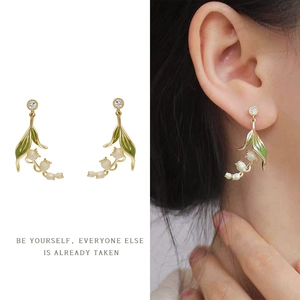 Detail of lily of the valley earrings with green leaves and pearls on model