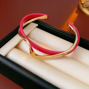 Close-up of double-layer wavy gold bangle with vibrant pink enamel in luxury display box