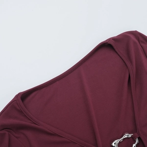 Detail of deep V-neck knit dress in burgundy with irregular silver metal buckle