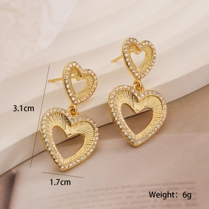 Detail view of double gold heart drop earrings with white zircons and radial texture