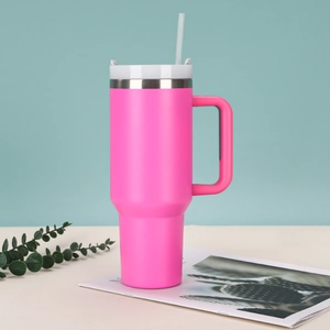 Pink 40oz stainless steel insulated tumbler with white lid and handle on desk