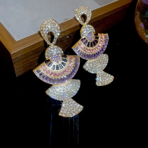 Close-up of luxury fan-shaped gold earrings with purple and pink zircon fringe details