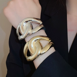 Close-up of interlocking hollow metal bangles in polished gold and silver finishes