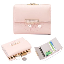 Pink tri-fold wallet detail showing floral patterns, card slots, and gold metal clasp