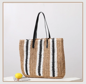 Detail of handwoven straw tote with black white brown stripes and leather handles