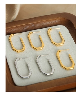 Macro view of geometric gold and silver titanium steel earrings on a wooden tray