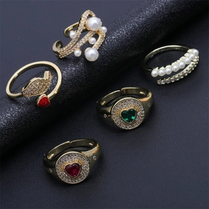 Détail de 5 bagues dorées avec cœurs, perles, ailes en zircon et anneaux réglables