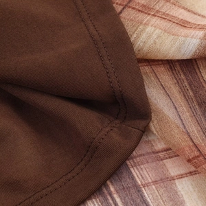 Detailed close-up of brown knit fabric and vintage plaid print sewing craftsmanship