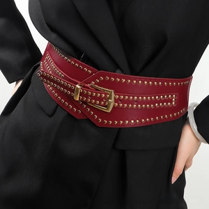 Close-up of wine red wide corset belt with gold studs and pin buckle on a blazer