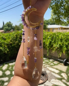 Detail of amethyst moon suncatcher with crystal prisms reflecting light in outdoor garden