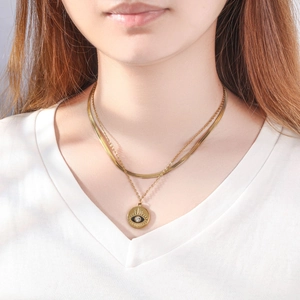 Dettaglio della collana a doppio strato dorata con ciondolo occhio del diavolo su una modella
