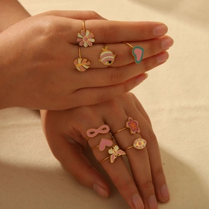 Colorful enamel flower and fish titanium steel ring set for women on beige fabric background