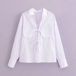 Détail d'une chemise blanche à manches longues avec double nœuds et bords volantés