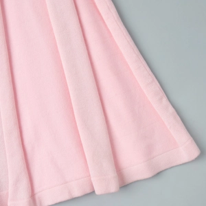 Close-up of pink knitted fabric texture and hem detail of a V-neck maxi dress