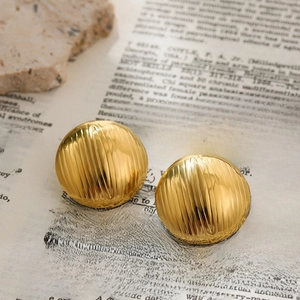 Macro shot of 18K gold plated convex earrings with striped texture on vintage book pages