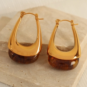 Retro teardrop earrings with gold metal and amber resin on stone background
