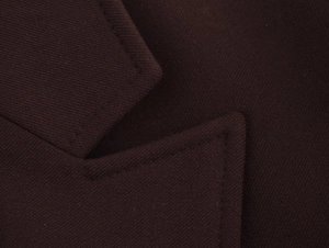 Makroaufnahme von dunkelbraunem Anzugstoff mit präzisen Nähten und feiner Textur