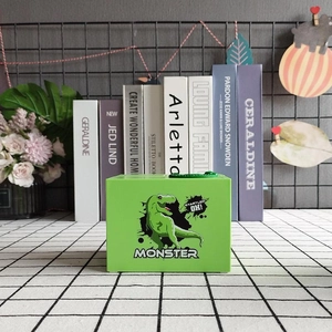 Detail view of a green dinosaur monster coin bank with text on a checkered background