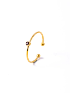 Detail of a minimalist gold ring featuring a deep red round gemstone in a bezel setting