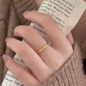 Minimalist twisted gold ring with square detail worn by a model on a warm background