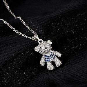 Cute bear pendant necklace with micro-paved zircons and blue stones on dark fabric