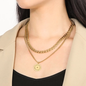 Detail of a gold-layered necklace with a flat cuban chain and a round zodiac pendant