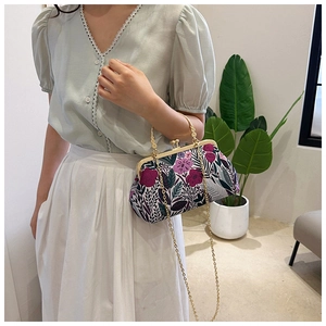 Detail of floral handbag with metal frame and chain strap shown in a lifestyle setting