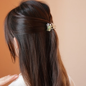 Detail of floral hair claw clip with light green petals and pearls on woman's hair