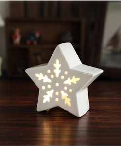 Close-up of ceramic star night light with snowflake cutouts on wooden surface