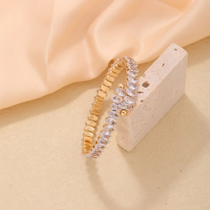 Golden open-wrap bracelet with pavé oval cubic zirconia stones on textured stone base