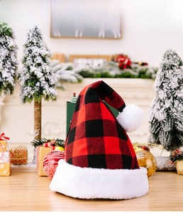 Detail of red and black buffalo plaid Christmas hat with plush white trim on wooden table