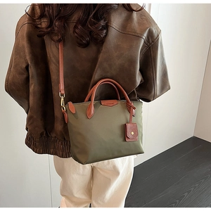 Olive green nylon tote bag featuring brown leather details and vintage gold hardware