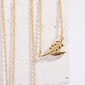 Detail of 18K gold lily of the valley flower pendant necklace on a white textured block