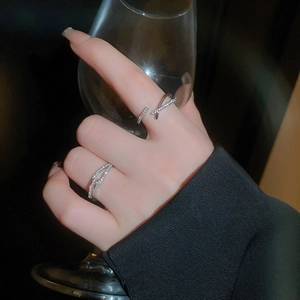 Détail de bagues croisées en argent avec zircone portées sur une tenue noire chic