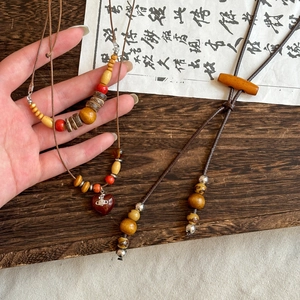 Macro detail of ethnic wooden beaded necklace with heart pendant and Saturn logo