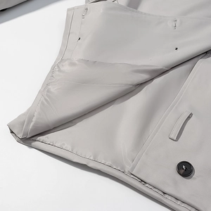 Detail of grey trench coat lining featuring premium stitching and black round button
