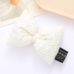 Close-up of a white padded puff pleated bow accessory with black woven label detail