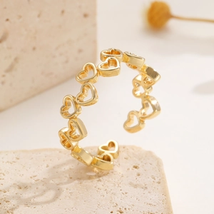 Vista macro di anello a cuore traforato placcato oro con fascia aperta regolabile