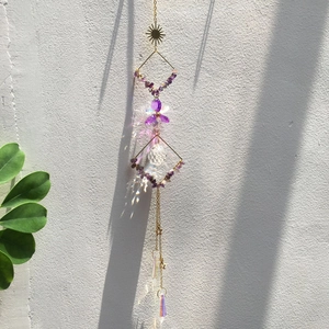 Amethyst crystal suncatcher casting rainbow light spots on white wall in sunlight