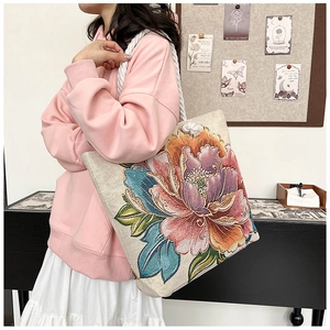 Detail of embroidered peony tote bag with sturdy cotton rope handles on model