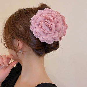 Detail of elegant dusty pink fabric camellia hair claw clip with layered petals on hair