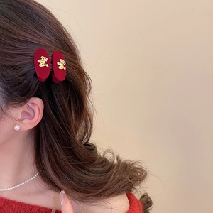 Close-up of model wearing plush burgundy triangle hair clips with gold bear charms