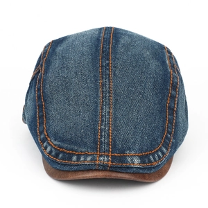 Close-up of blue denim beret with brown leather brim and contrast orange stitching