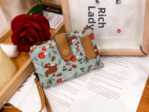 Close-up of mint green canvas wallet featuring squirrel and mushroom forest patterns