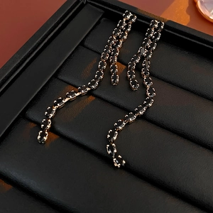 Macro shot of long black beaded tassel earrings on a textured display stand