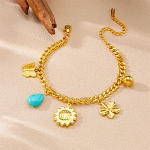Détail du bracelet en acier doré avec breloques papillon, turquoise et fleurs