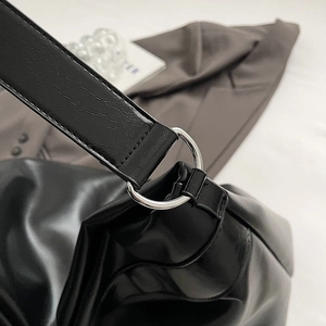 Vue détaillée de la boucle en métal argenté sur la bandoulière du sac en cuir noir