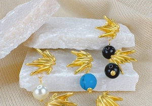 Gros plan détaillé de boucles d'oreilles dorées avec perles et turquoise sur pierre